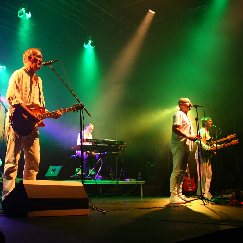 Genesis tribute band 'G2 Genesis' perform on stage under neon lights.