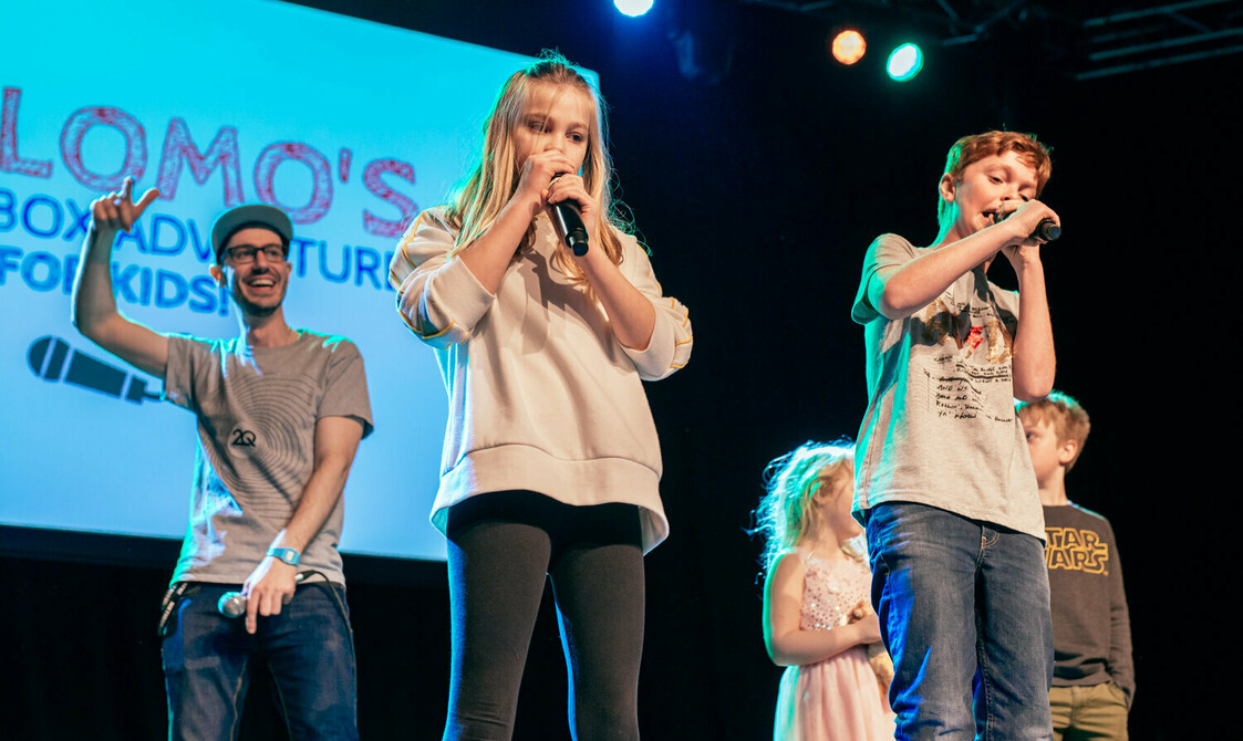 A group of children stand on stage with microphones for Beat Box Adventure for Kids.