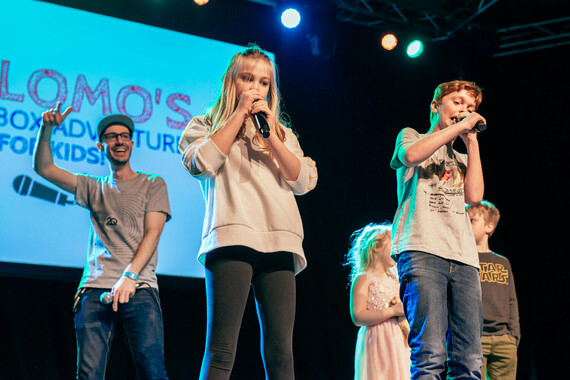 A group of children stand on stage with microphones for Beat Box Adventure for Kids.