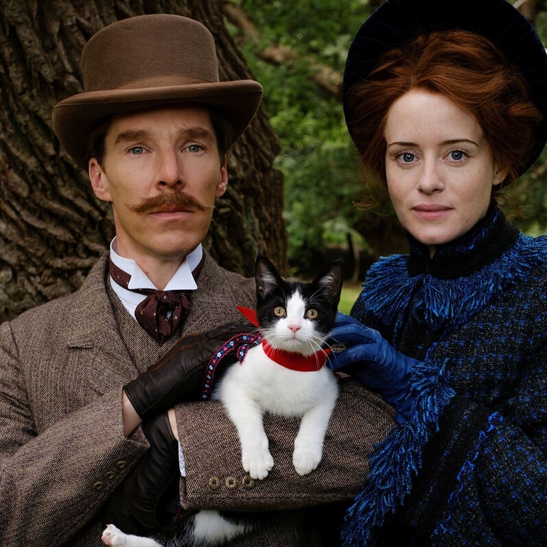 Benedict Cumberbatch and Claire Foy in period costume holding a black and white cat