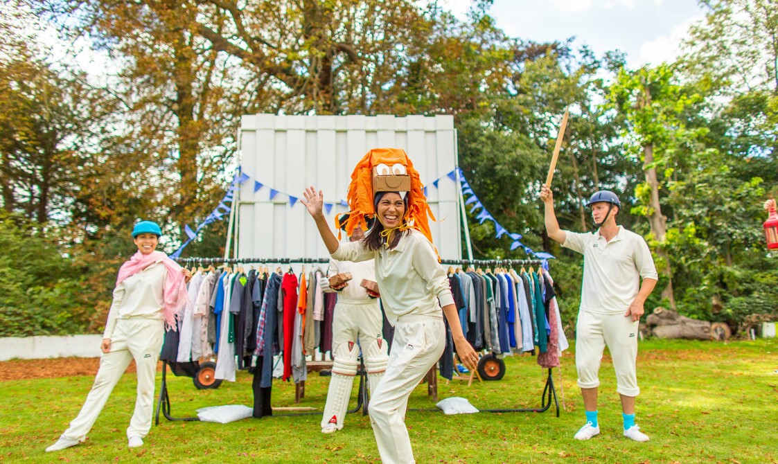 4 actors in cricket whites perform on a cricket green using and wearing props