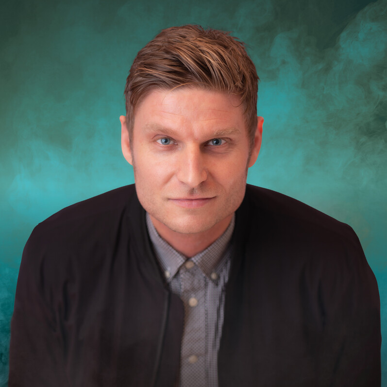A head shot of comedian, Scott Bennett in front of a green background.