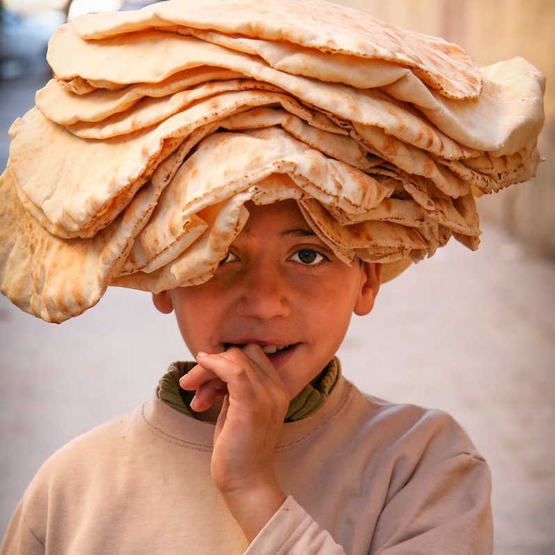 Young Syrian Boy with flatbreads piled on his head