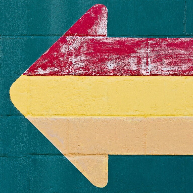 unsplash logo with multicolored arrow on a blue brick wall