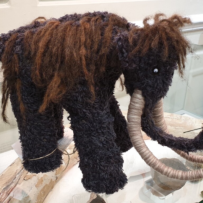 A woolly mammoth character on a glass display case