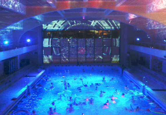 A light party in a large indoor swimming pool with swimming using floats.
