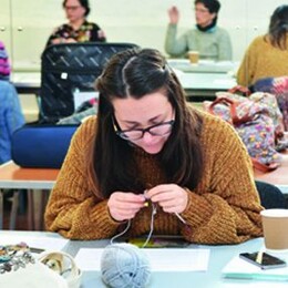 A woman sat in a workshop knitting