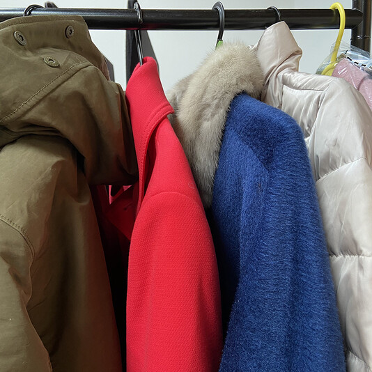 A number of different coats hung up on a rail