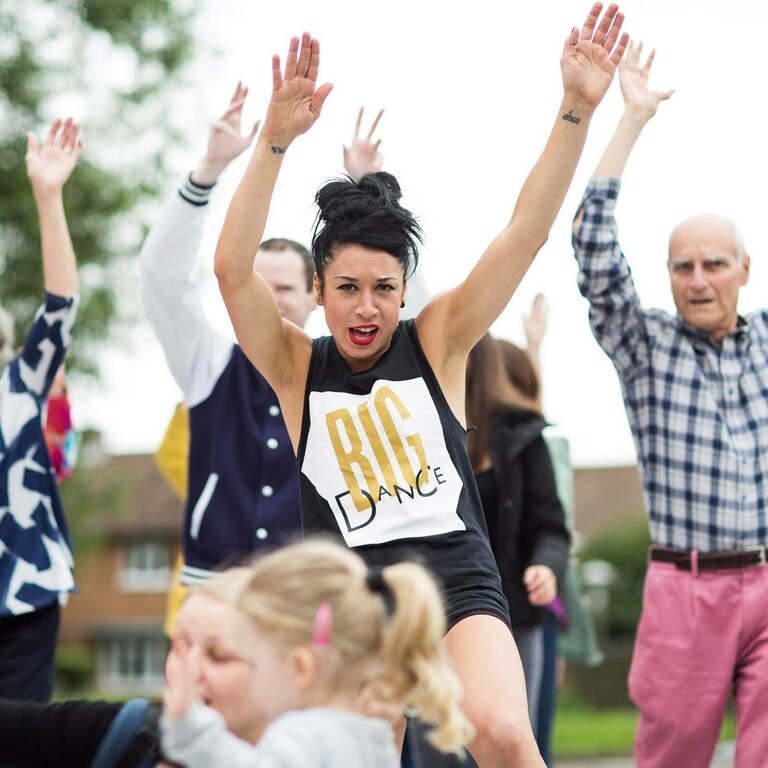 A group of performers and audience members join in for an outside dance workshop
