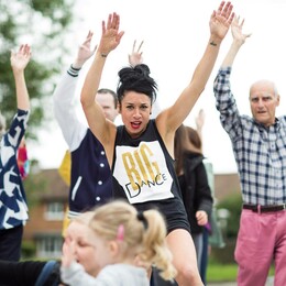 A group of performers and audience members join in for an outside dance workshop