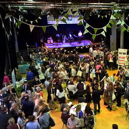 Large event hall filled with people, tables, tents and decorations