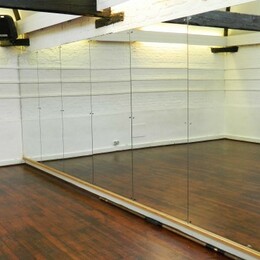An empty dance studio hall with a long wall of mirrors