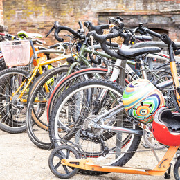 Collection of multicoloured Bikes and scooters in a courtyard