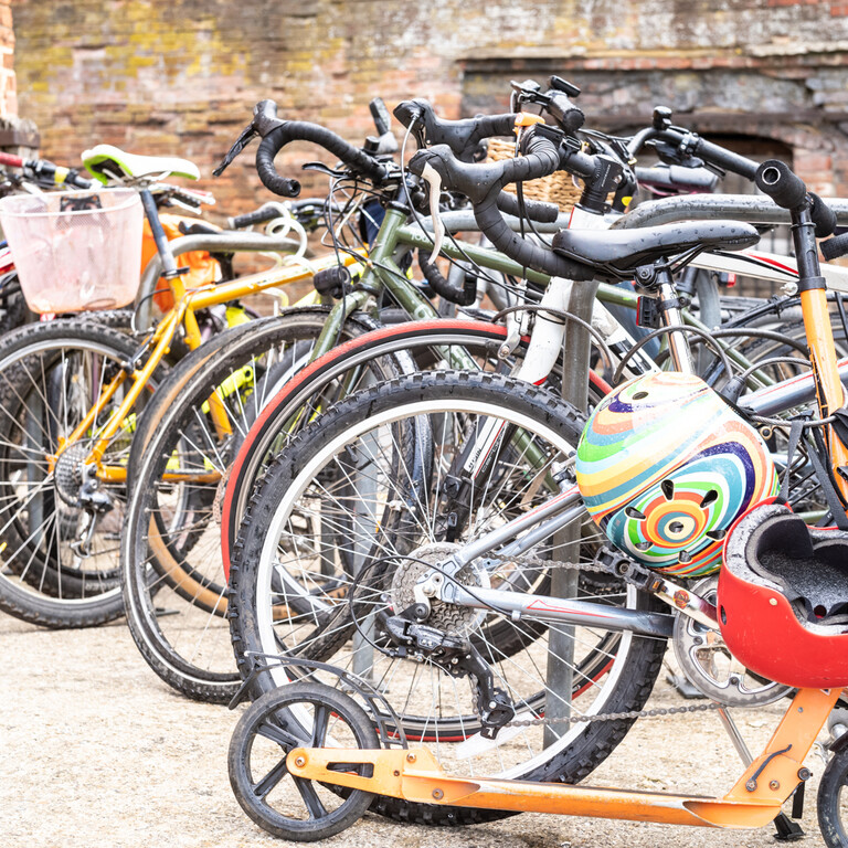 Collection of multicoloured Bikes and scooters in a courtyard