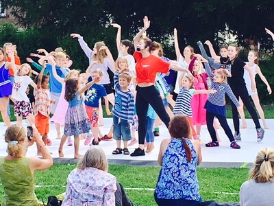 A group of children following a leader in a dance workshop outside