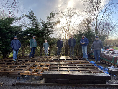 Men in Sheds group standing around large wooden panels