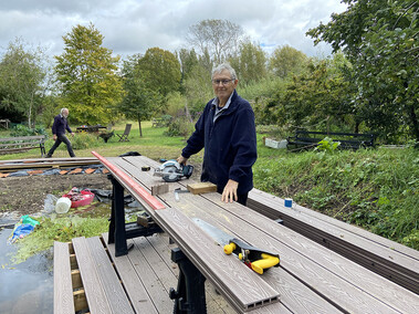 Member of Men in Sheds working on wooden planks
