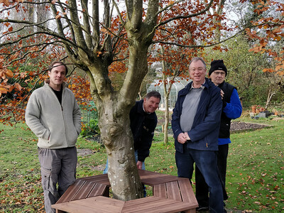 The Men in Sheds group gathered around the tree bench